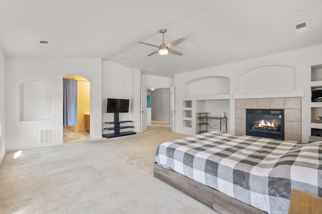 bedroom with lofted ceiling, visible vents, light carpet, and a tiled fireplace