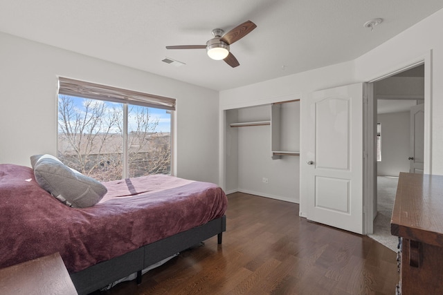 bedroom featuring ceiling fan, wood finished floors, visible vents, baseboards, and a closet