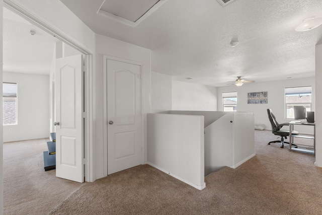 interior space with carpet floors, a textured ceiling, and an upstairs landing