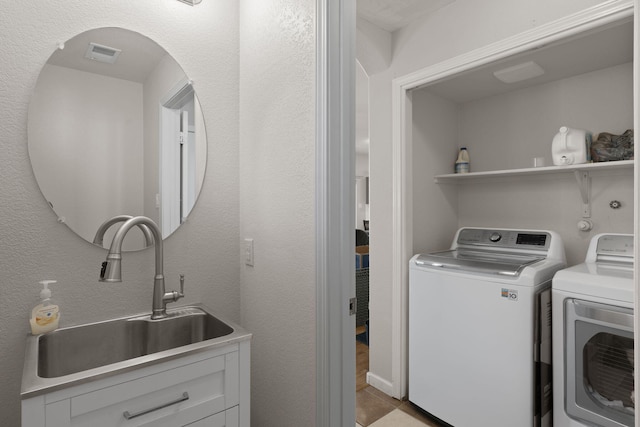 washroom with light tile patterned flooring, laundry area, a sink, visible vents, and washing machine and clothes dryer