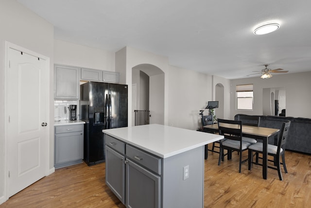 kitchen with arched walkways, black fridge with ice dispenser, and gray cabinetry