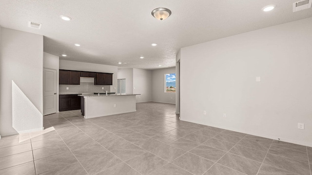 unfurnished living room with a textured ceiling, light tile patterned flooring, visible vents, and recessed lighting