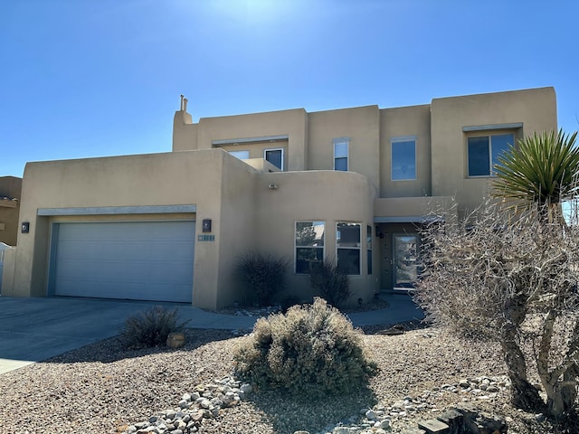 southwest-style home featuring an attached garage, concrete driveway, and stucco siding