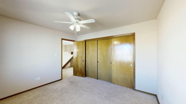 unfurnished bedroom featuring a closet, carpet, a ceiling fan, and baseboards