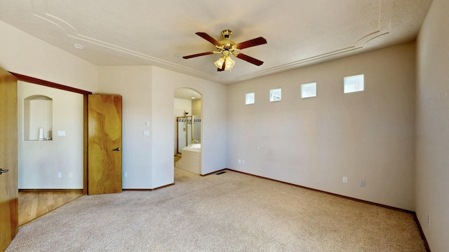 empty room featuring baseboards, arched walkways, a ceiling fan, and carpet flooring