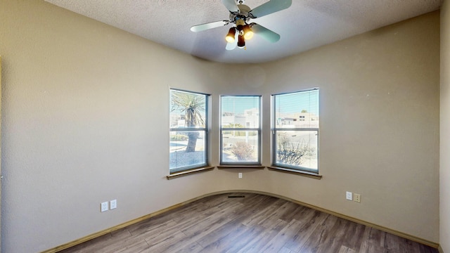 unfurnished room with a ceiling fan, a textured ceiling, baseboards, and wood finished floors