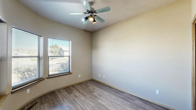 unfurnished room featuring a textured ceiling, ceiling fan, light wood-type flooring, and baseboards