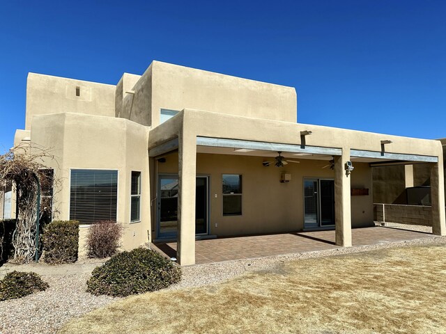 rear view of house with ceiling fan, a patio area, and stucco siding