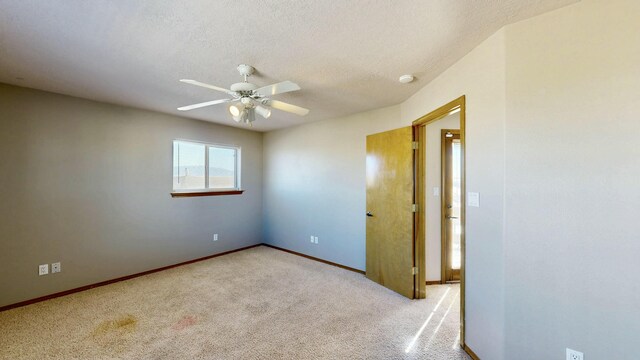 empty room with baseboards, a textured ceiling, a ceiling fan, and carpet flooring