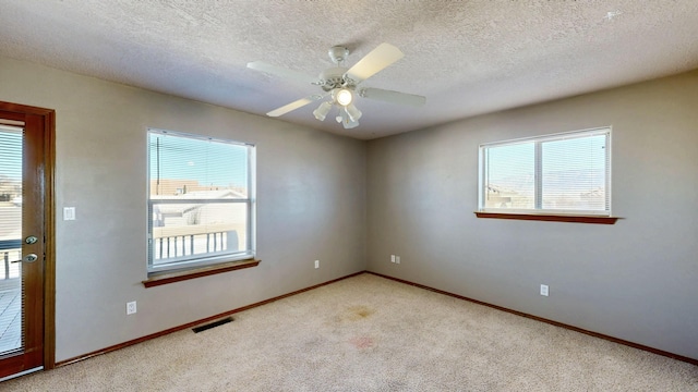 empty room with carpet floors, plenty of natural light, visible vents, and a ceiling fan