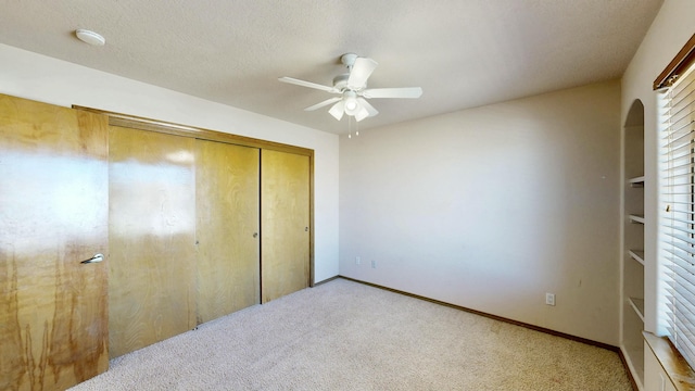 bedroom featuring arched walkways, a textured ceiling, light carpet, baseboards, and a closet