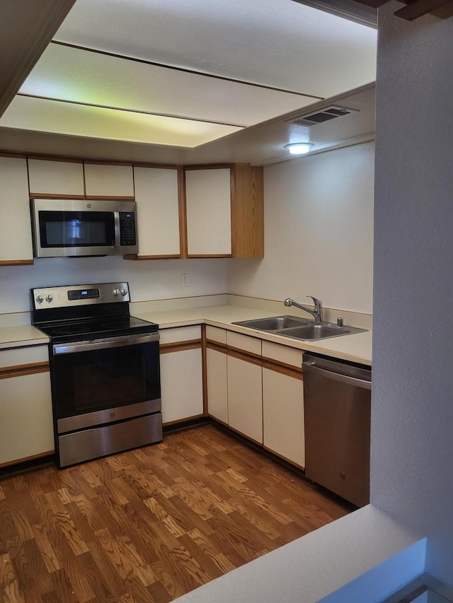 kitchen featuring visible vents, appliances with stainless steel finishes, dark wood-style flooring, light countertops, and a sink