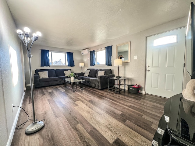 living area featuring dark wood-type flooring, a wall mounted air conditioner, a textured ceiling, and baseboards