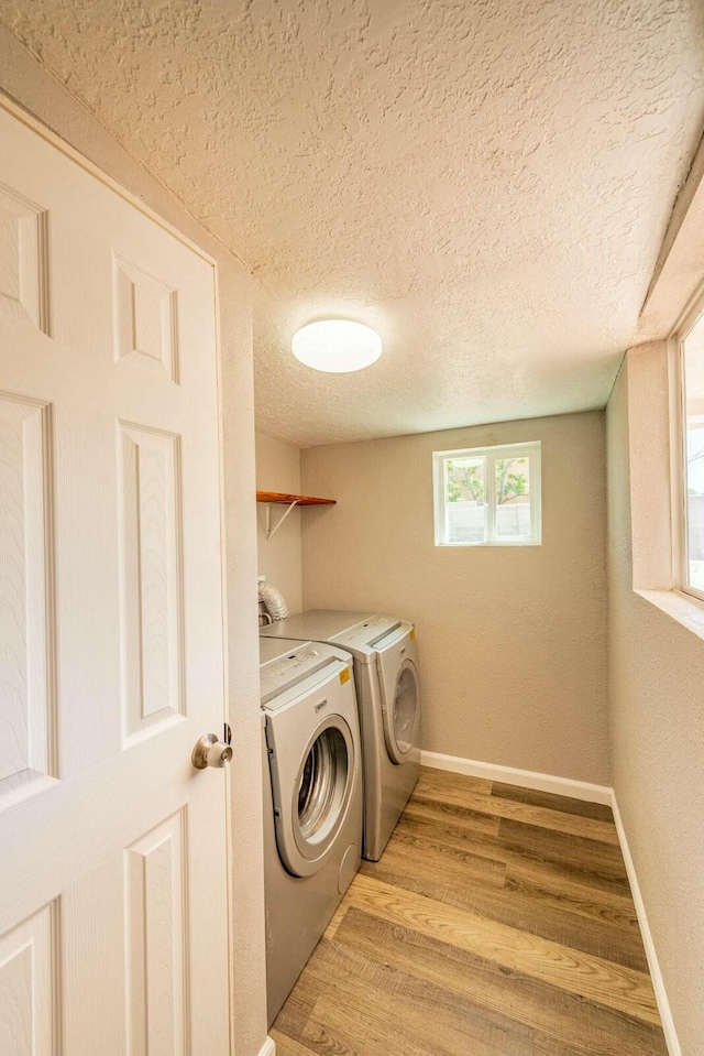 laundry area with laundry area, baseboards, light wood-style flooring, a textured ceiling, and washing machine and dryer