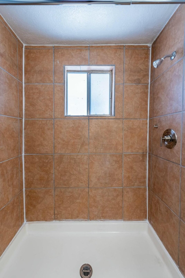 bathroom with a tile shower and a textured ceiling