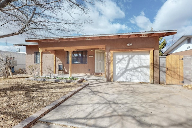 view of front of property with an attached garage, a gate, concrete driveway, and stucco siding