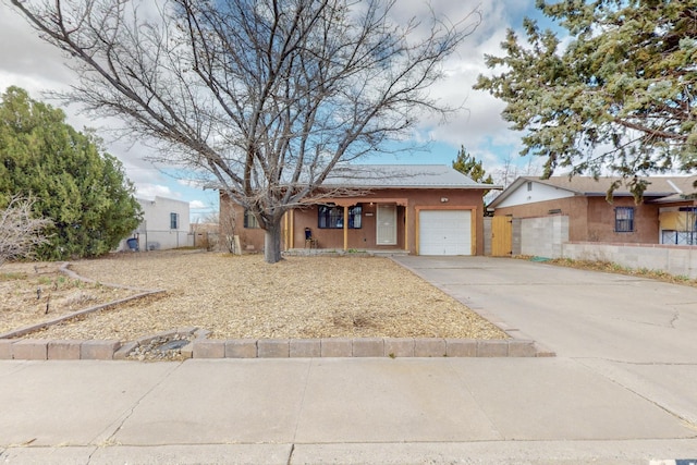 ranch-style home featuring an attached garage, fence, concrete driveway, and stucco siding