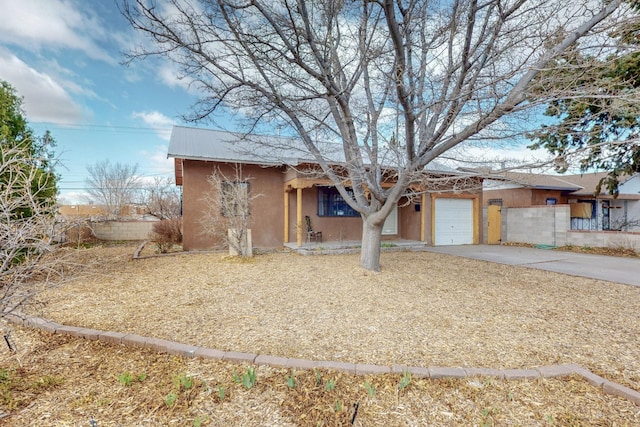 view of front of property with metal roof, an attached garage, fence, concrete driveway, and stucco siding