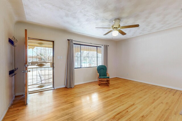 unfurnished room with light wood finished floors, a textured ceiling, baseboards, and a ceiling fan