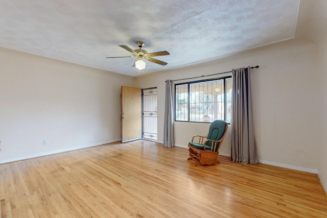 unfurnished room with light wood-style floors, ceiling fan, baseboards, and a textured ceiling