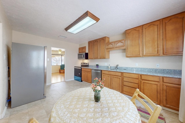 kitchen with baseboards, visible vents, appliances with stainless steel finishes, a textured ceiling, and a sink