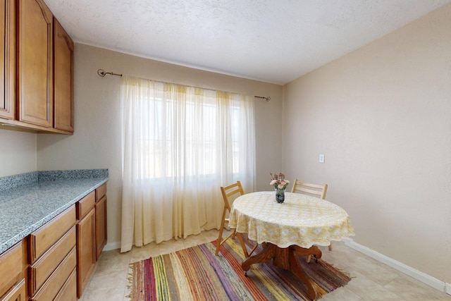 dining space featuring a textured ceiling, light tile patterned floors, and baseboards