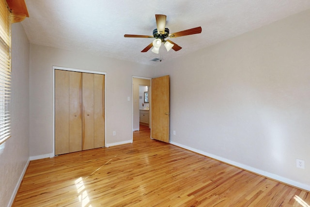 unfurnished bedroom with baseboards, a closet, a ceiling fan, and light wood-style floors