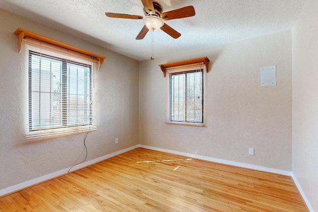 spare room featuring baseboards, a textured wall, ceiling fan, wood finished floors, and a textured ceiling