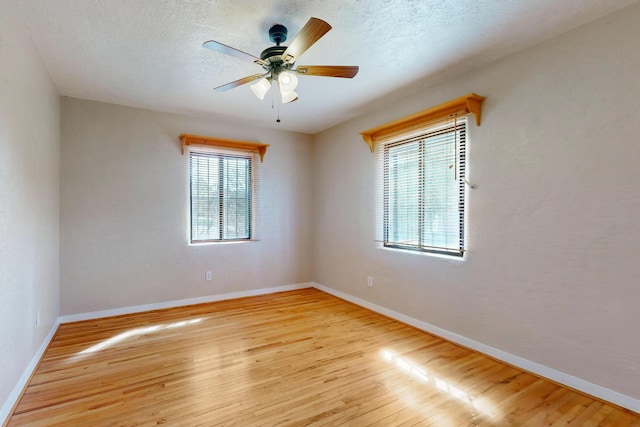 spare room featuring a textured ceiling, wood finished floors, a ceiling fan, and baseboards