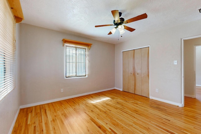 unfurnished bedroom with a textured ceiling, light wood finished floors, a closet, and baseboards