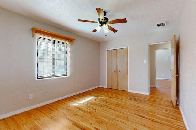 unfurnished bedroom with baseboards, a textured ceiling, visible vents, and light wood-style floors