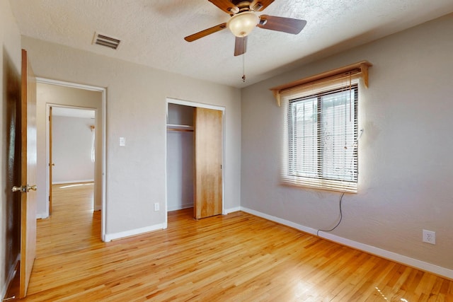 unfurnished bedroom featuring a textured ceiling, light wood-type flooring, visible vents, and baseboards