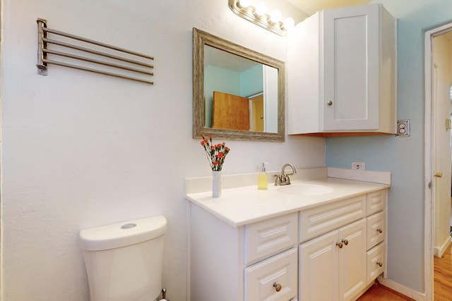 bathroom with baseboards, vanity, and toilet