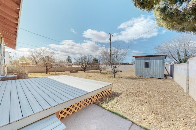 view of yard with an outbuilding, a fenced backyard, a deck, and a storage shed