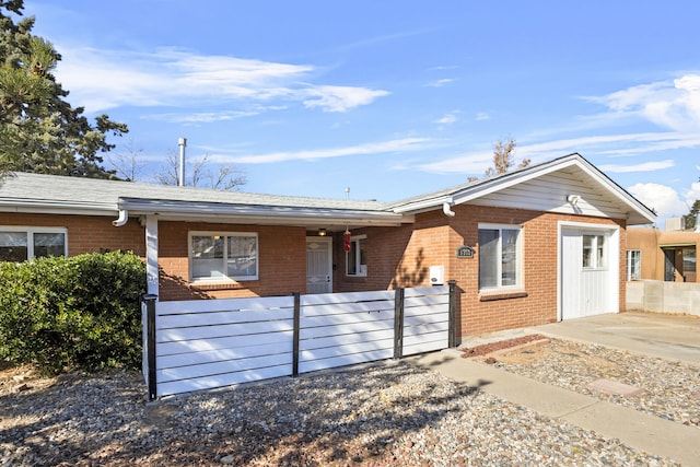 ranch-style home with a fenced front yard and brick siding