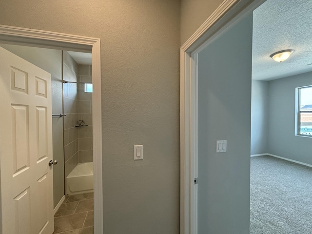 full bath with a textured ceiling, shower / bathtub combination, tile patterned flooring, and baseboards