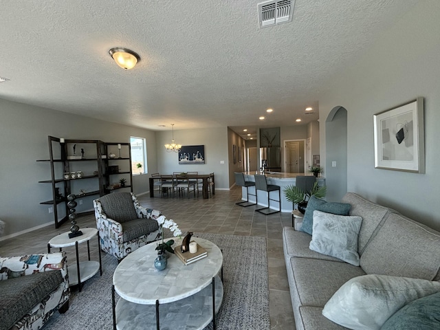 living room featuring arched walkways, baseboards, visible vents, and a notable chandelier