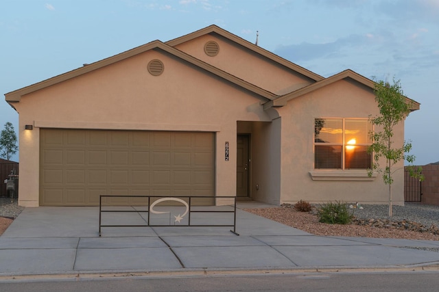 single story home with concrete driveway, fence, an attached garage, and stucco siding