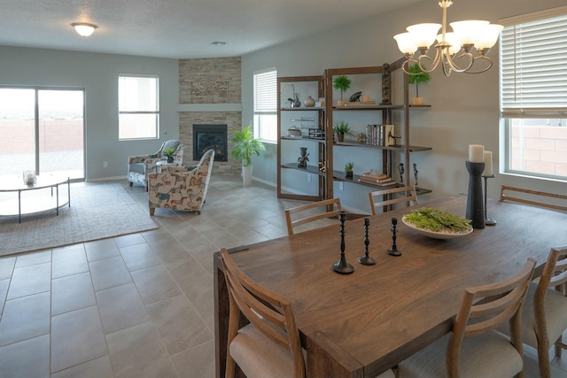 tiled dining area with a chandelier, a fireplace, and baseboards