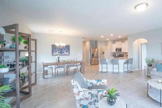 living room with arched walkways, light tile patterned floors, a chandelier, recessed lighting, and baseboards