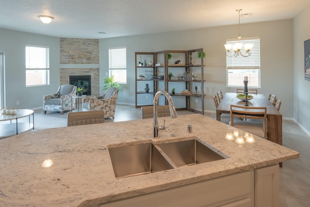 kitchen featuring a healthy amount of sunlight, light stone countertops, pendant lighting, and a sink