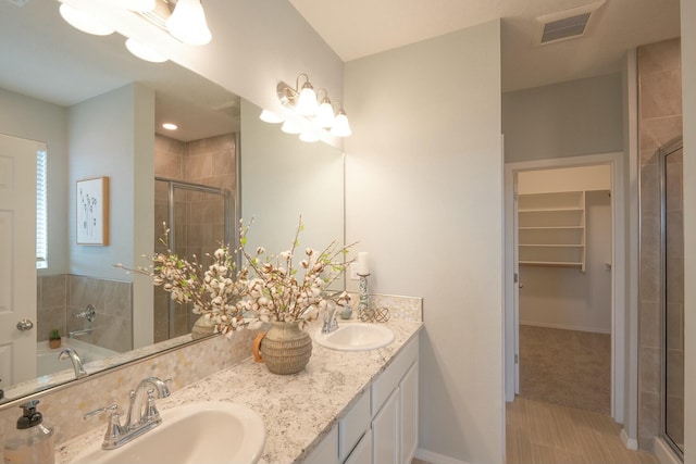 full bath featuring a shower stall, visible vents, a walk in closet, and a sink