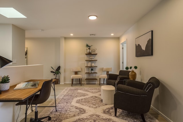 living area featuring a skylight, baseboards, wood finished floors, and recessed lighting