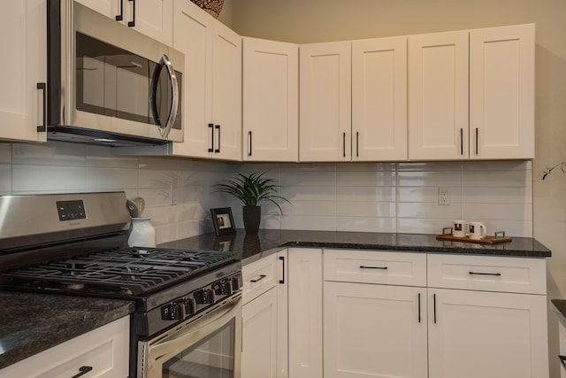 kitchen featuring white cabinetry, stainless steel appliances, decorative backsplash, and dark stone counters