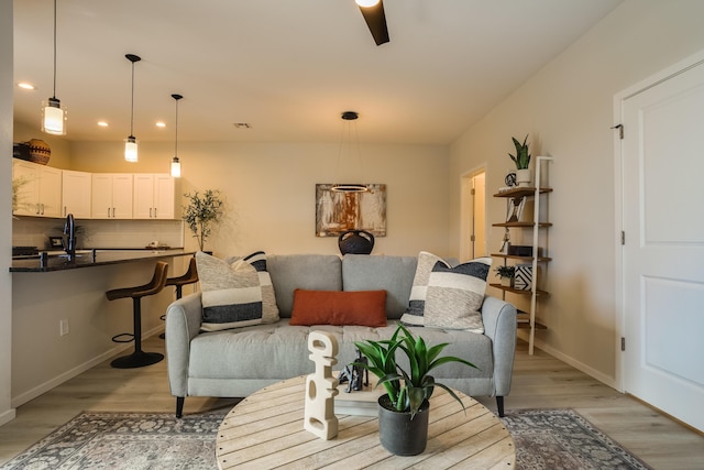 living room featuring light wood-style flooring, baseboards, and recessed lighting