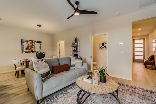 living area featuring a ceiling fan, light wood-style flooring, and baseboards