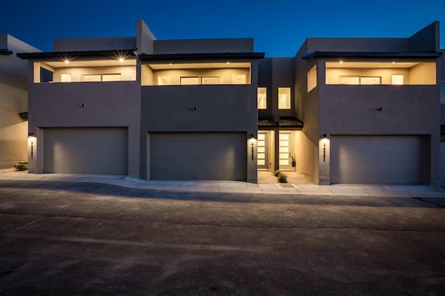 view of front facade featuring a balcony, an attached garage, and stucco siding