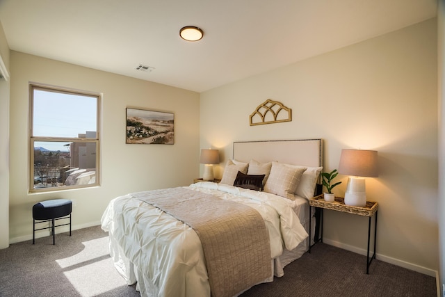 bedroom with dark colored carpet, visible vents, and baseboards