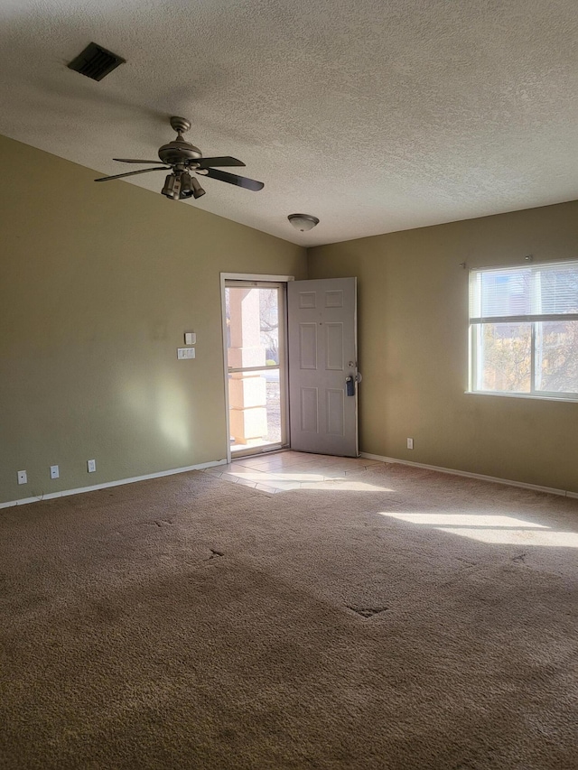 carpeted spare room with baseboards, visible vents, ceiling fan, and a textured ceiling