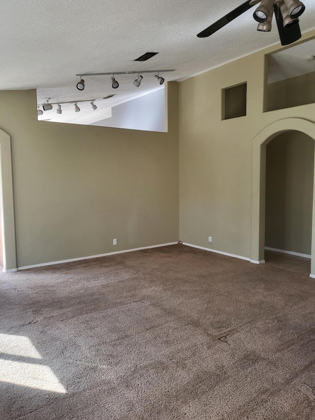 carpeted empty room featuring baseboards, a textured ceiling, arched walkways, and a ceiling fan